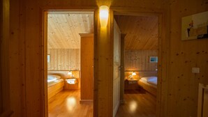 Eine Holzhütte mit zwei Schlafzimmern, jeweils mit Nachttischlampe und kleinem Nachttisch.