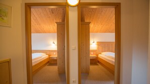 Ein Zimmer mit einem Schrank mit Spiegel, zwei Betten, Nachttischlampen und Teppichboden.