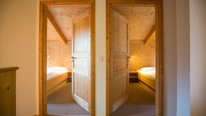 A narrow hallway with two wooden doors leading to bedrooms. Each room has a single bed and a nightstand.