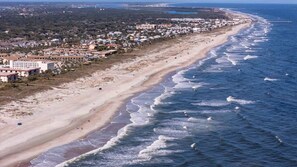 Uma cidade costeira com uma orla marítima, edifícios e uma praia de areia.