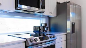 Cozinha moderna com micro-ondas embutido, cafeteira e eletrodomésticos de aço inoxidável.