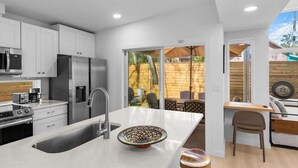 A modern kitchen with white cabinets, stainless steel appliances, and a large island with a bowl. - The Hidden Gem of Old City - Team Joseph Ellen (St Augustine)