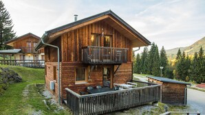 A two-story wooden cabin with a balcony, a hot tub, and a deck.