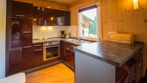 A modern kitchen with wooden cabinets, a stainless steel oven, a sink, and a window providing natural light.
