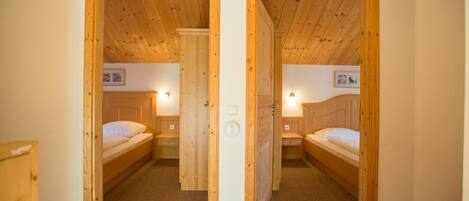 A room with two wooden bunk beds, a carpeted floor, and a wooden ceiling.