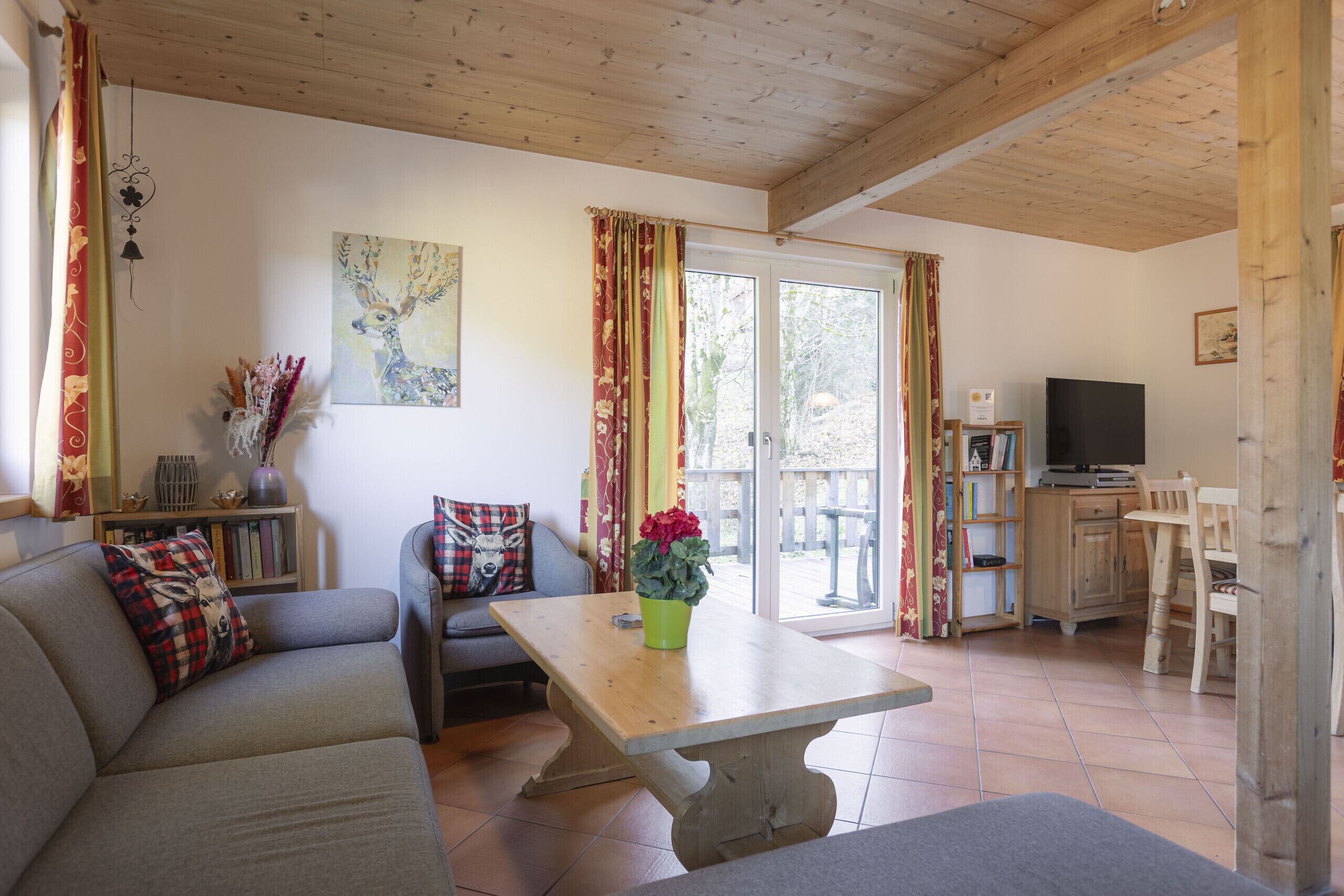 Ein gemütliches Wohnzimmer mit einer Couch, einem Holztisch und einem Fernseher im Hintergrund.