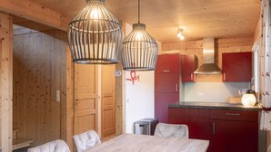 A wooden interior with a dining table, chairs, red cabinets, and hanging light fixtures. - Chalet # 92 with 3 BR for up to 6 people (Annaberg)