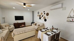 Un salon moderne comprenant un ensemble canapé, une table à manger pour deux personnes, un téléviseur à écran plat et des œuvres d’art décoratives accrochées au mur.