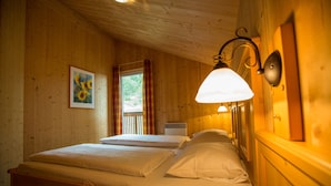 Une chambre dans un chalet en bois, avec deux lits, un tableau et une fenêtre avec des rideaux.