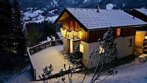 Une cabane en bois dotée d’un balcon, entourée de montagnes enneigées.