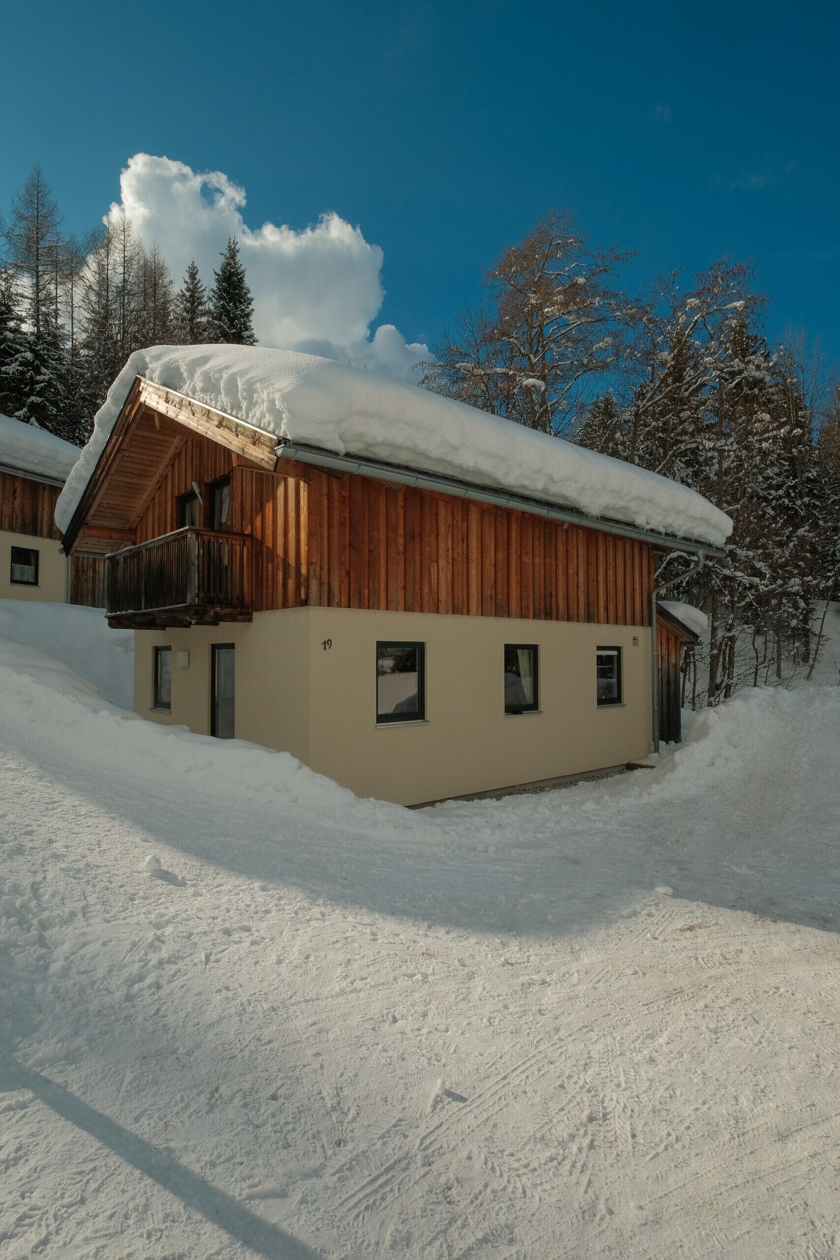 Una cabaña de madera con balcón, rodeada de árboles cubiertos de nieve.