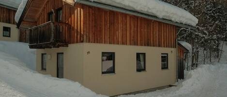 Una cabaña de madera con balcón, rodeada de árboles cubiertos de nieve.
