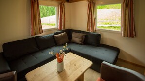 Een moderne woonkamer met een donkergrijze modulaire bank, een houten salontafel en een vaas met bloemen.
