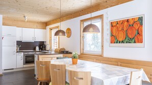A modern kitchen with wooden cabinets, a built-in oven, and a dining area with a large table and chairs. - Chalet # 95 with 3 BR for up to 8 people (Annaberg)
