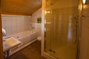 A bathroom with a bathtub, toilet, and glass-enclosed shower area. - Chalet # 95 with 3 BR for up to 8 people (Annaberg)