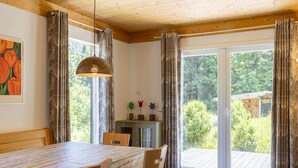 A dining area with a table and chairs, a hanging light fixture, and a view of the outdoors through a sliding glass door. - Chalet # 95 with 3 BR for up to 8 people (Annaberg)