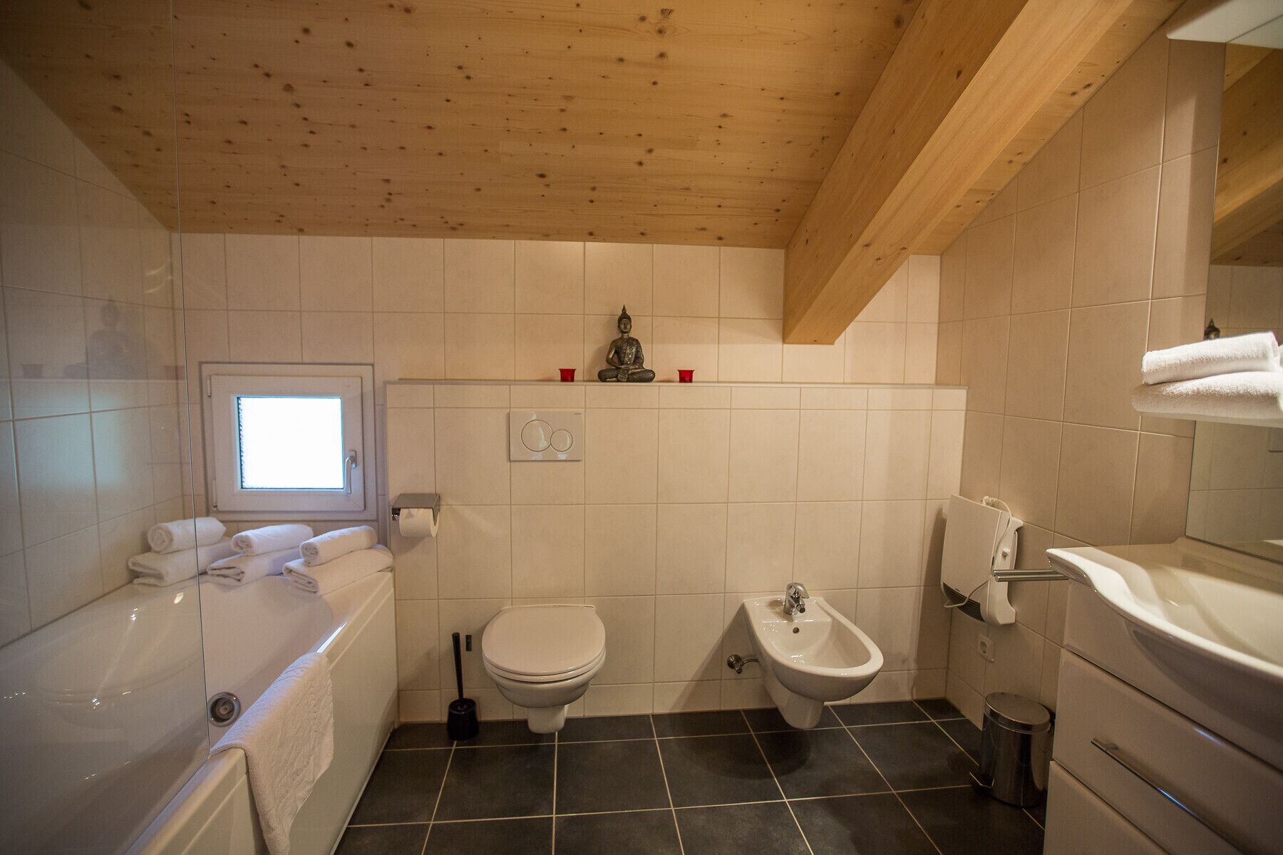 Une salle de bain avec une baignoire, des toilettes, un bidet et une fenêtre.