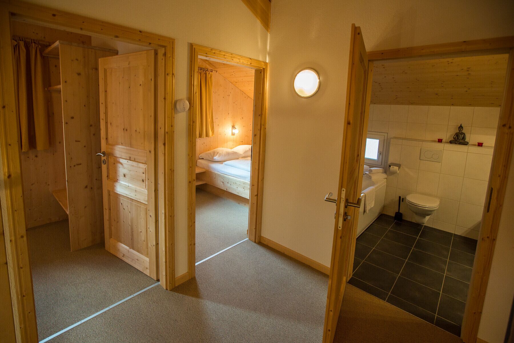 Un intérieur en bois avec un lit, une salle de bain et une petite fenêtre.