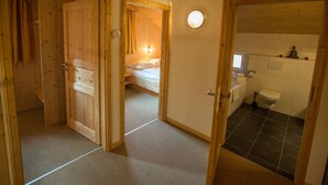 Un intérieur en bois avec un lit, une salle de bain et une petite fenêtre.