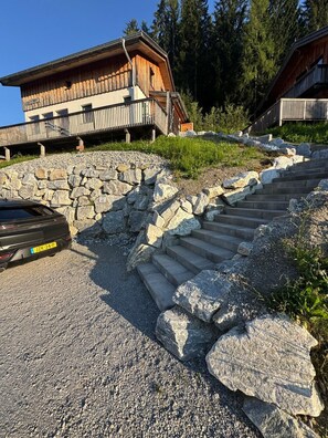 Un edificio con una escalera de piedra que conduce a una terraza de madera, rodeado de árboles.