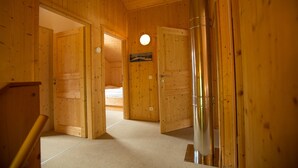 A wooden interior with a bed, a door, and a cylindrical object on the floor.