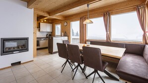 A cozy cabin interior with a dining area, kitchen, and a fireplace.