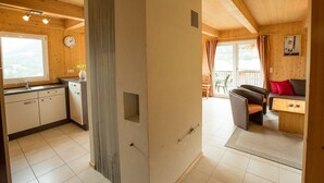 A wooden interior with a kitchen, dining area, and a view through a large window.