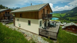 A chalet with a balcony, a deck, and a view of a valley.