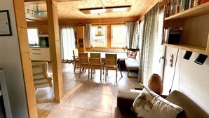 Interior acogedor de una cabaña con comedor, sofá y estantería.