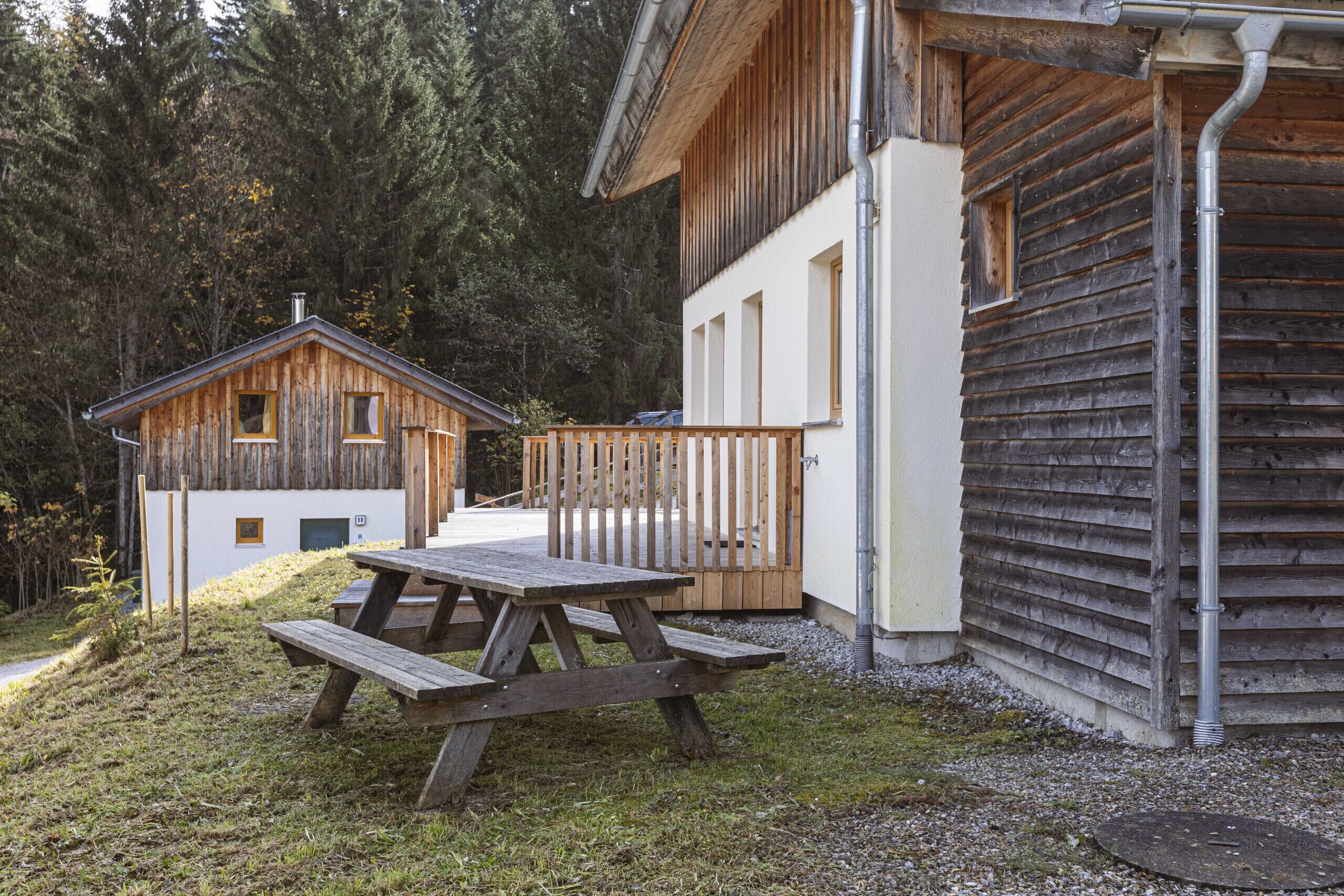 A wooden cabin with a picnic table in front, surrounded by trees.