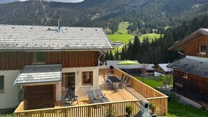 Un chalet doté d’une terrasse, offrant une vue sur la montagne et dont l’extérieur est en bois.