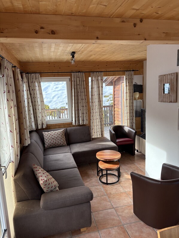 A cozy living room with a sectional sofa, a round wooden table, and a leather chair. - Chalet # 82 with 4 BR for up to 8 people (Annaberg)