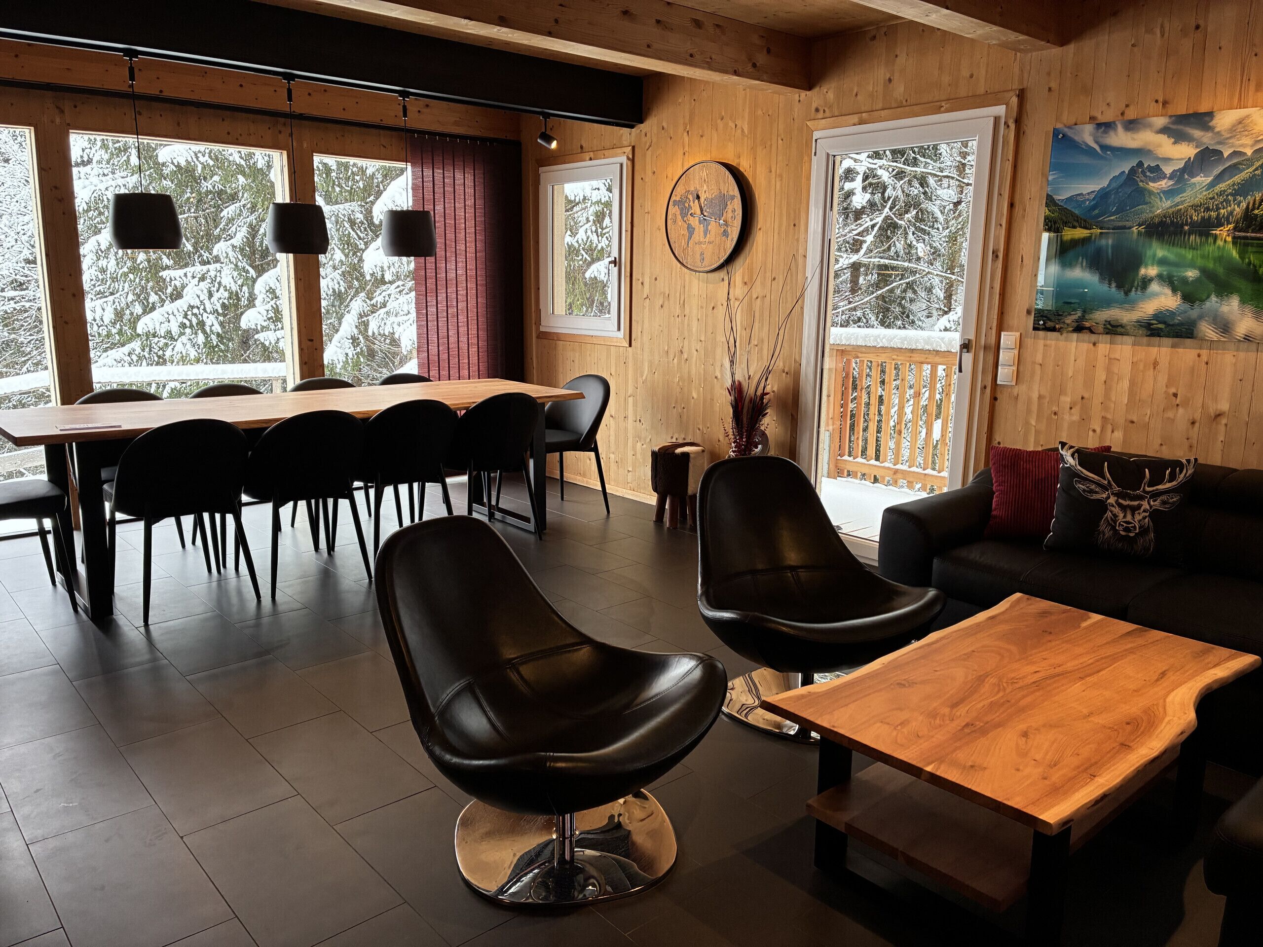 A modern interior with a wooden dining table, black chairs, a leather sofa, and a wooden coffee table.