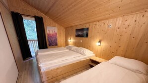 Una habitación de cabaña de madera con dos camas, una ventana con cortinas y un cartel en la pared.