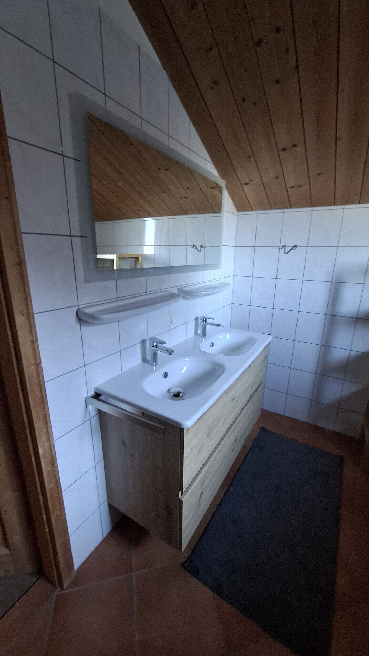 A bathroom with two sinks, a mirror, and a wooden ceiling.