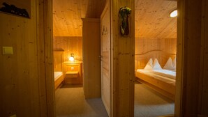 A wooden cabin with a single bed, a bedside table with a lamp, and a small bathroom. - Chalet # 75 with 3 BR for up to 6 people (Annaberg)