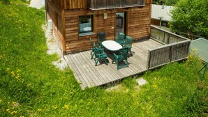 A wooden cabin with a balcony, a deck with outdoor furniture, and a view of the surrounding landscape. - Chalet # 75 with 3 BR for up to 6 people (Annaberg)