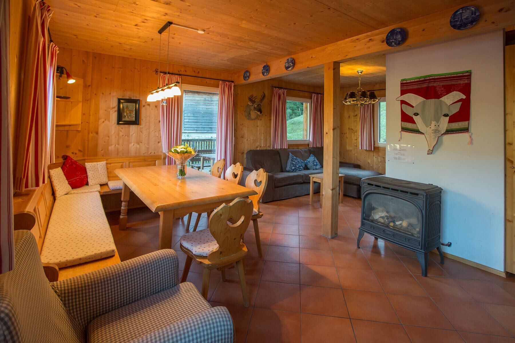 Ein gemütliches Blockhaus-Interieur mit einem Holztisch, einer Couch, einem Kamin und einer Wand mit Tierköpfen.