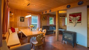 Ein gemütliches Blockhaus-Interieur mit einem Holztisch, einer Couch, einem Kamin und einer Wand mit Tierköpfen.