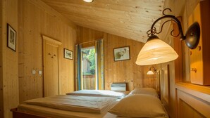 Une chambre dans une cabane en bois, avec un lit, un luminaire au plafond et une vue sur l’extérieur.