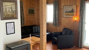 Un salon chaleureux avec une cheminée, des murs en bois et un canapé.