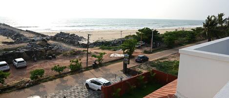 A residential area with a view of the beach, parked cars, and a gated entrance.