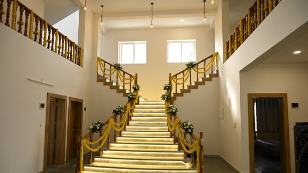 Un magnifique escalier avec une rampe en bois, orné de guirlandes jaunes et de compositions florales.