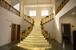 A grand staircase with a wooden handrail, decorated with yellow garlands and floral arrangements.