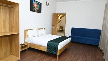Un dormitorio con una cama de madera, un sofá azul, un armario de madera y una escalera que lleva a otra habitación.