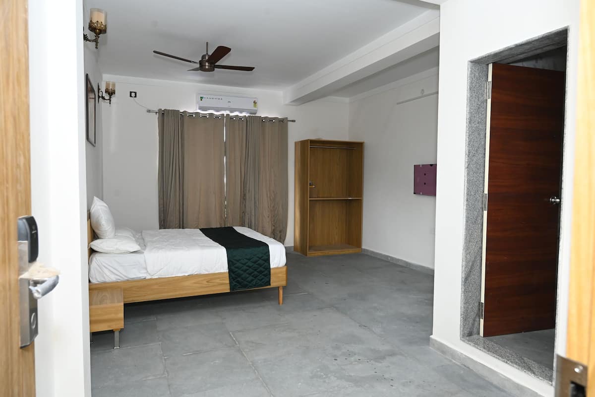 A hotel room with a bed, a wardrobe, a ceiling fan, and an air conditioning unit.