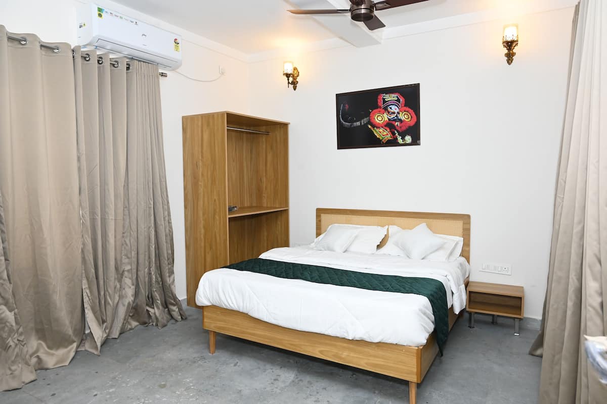 A bedroom with a wooden bed, beige curtains, a wall-mounted air conditioner, a ceiling fan, and a wall-mounted light fixture.