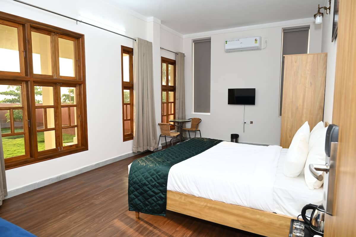A bedroom with a bed, wooden wardrobe, TV, and a window with curtains.