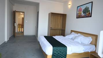 Un dormitorio con una cama, un armario de madera, una manta verde y un cuadro colgado en la pared.