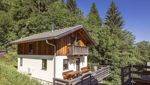 Une cabane dotée d’un balcon, d’une terrasse en bois et offrant une vue sur la forêt environnante.